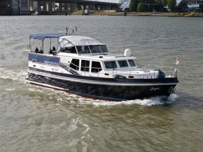 motorjacht varend op rivier met brug op achtergrond