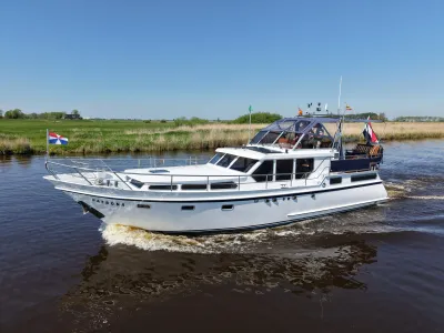 wit motorjacht op kanaal bij grasland