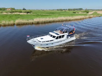 motorjacht varend op een rivier bij grasland
