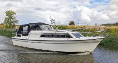 motorjacht in kanaal met oevers en bewolkte lucht
