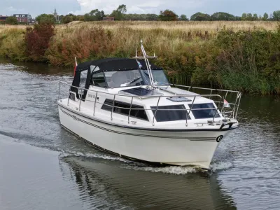 Motorjacht varend op een rivier langs oever