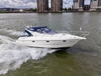 witte motorboot varend op rivier met gebouwen