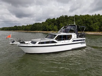 wit motorjacht op kanaal bij bomen