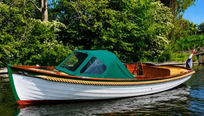 houten sloep met groene kuiptent op het water