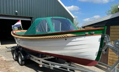 witte sloep op trailer bij loods