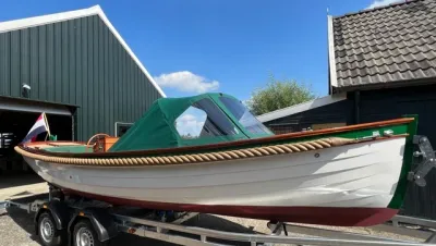 sloep met kuiptent op trailer bij loods