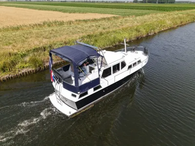 Motorjacht varend op kanaal langs landbouwgrond