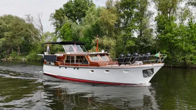 motorjacht op een rivier bij beboste oever