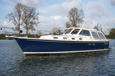 blauw-wit motorjacht op rustig water bij oever