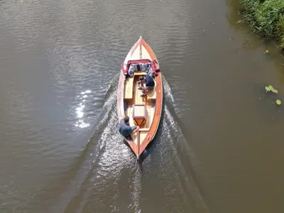 houten sloep op kanaal met twee personen