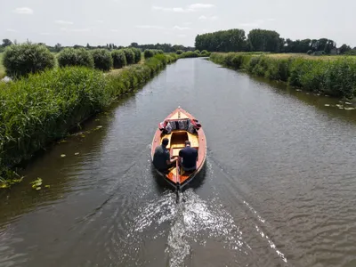houten sloep met twee personen op kanaal