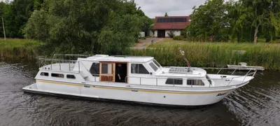 witte motorboot bij oever en huis