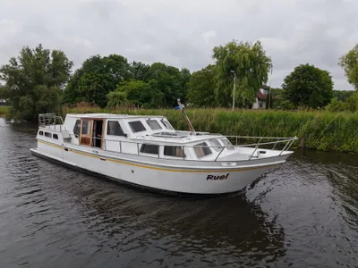wit motorjacht op rivier met riet en bomen