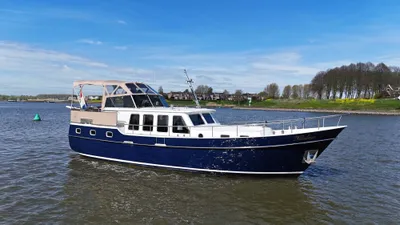 blauw-wit motorjacht op rivier met oever op achtergrond