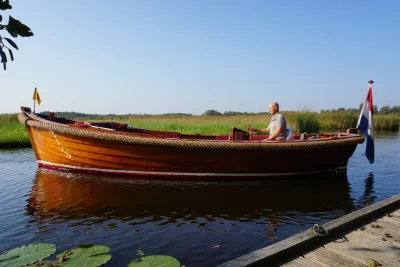 houten sloep op rustig water met bestuurder