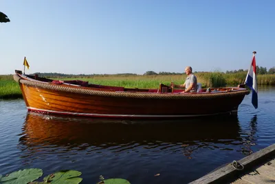 houten sloep op kalm water met bestuurder