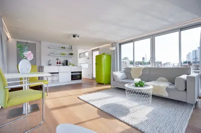 ruime woonkamer met grote ramen en keuken