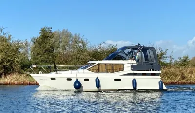 wit motorjacht op water langs oever