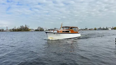 houten motorboot op open water bij de oever