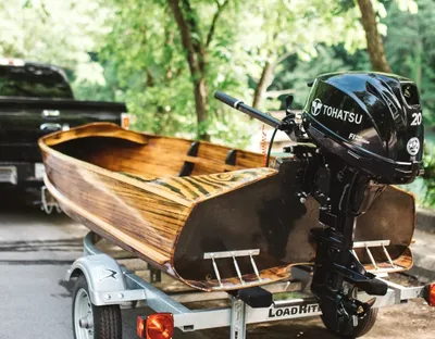 houten boot met buitenboordmotor op trailer