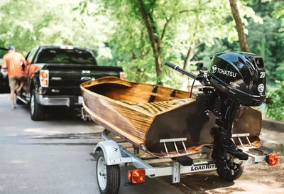 houten boot met buitenboordmotor op aanhangwagen