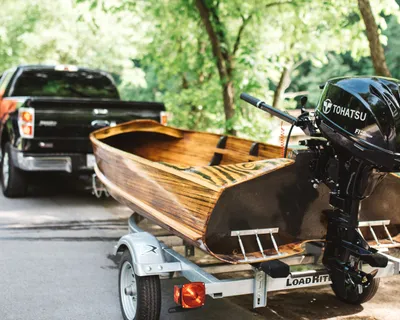 houten boot met buitenboordmotor op trailer