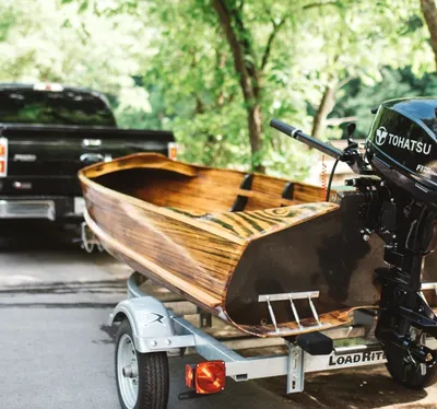 houten boot op trailer naast een auto