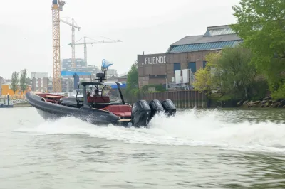 snelvarende motorboot op rivier bij industrie