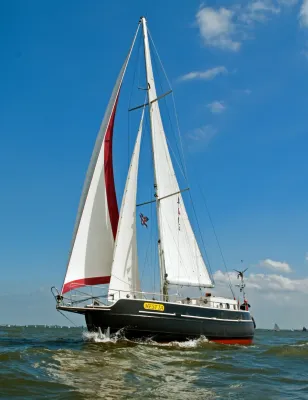 zeiljacht op open water met witte en rode zeilen