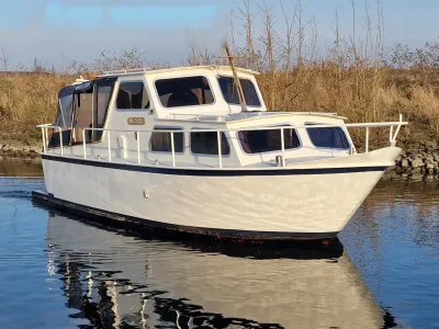 witte kruiser liggend op water bij oever