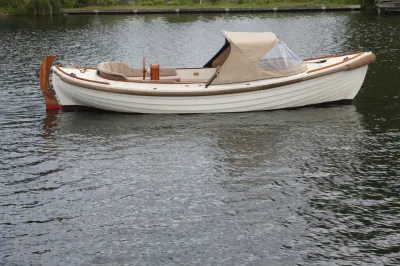 witte houten sloep met beige kap op water