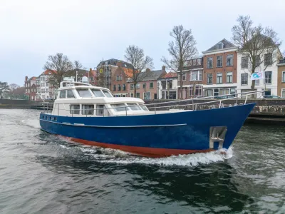 blauw motorjacht varend langs stadswal