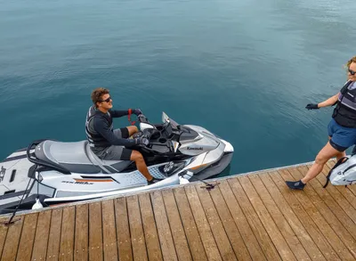 Jetski naast houten steiger met twee personen