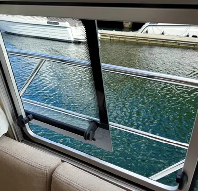 uitzicht door kajuitraam op railing en water