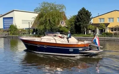 motorjacht varend op kanaal met huizen op oever