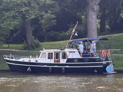 motorjacht afgemeerd bij oever met bomen
