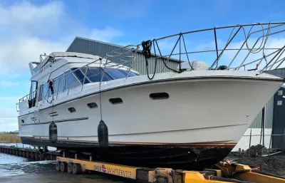 grote motorkruiser op trailer bij loods