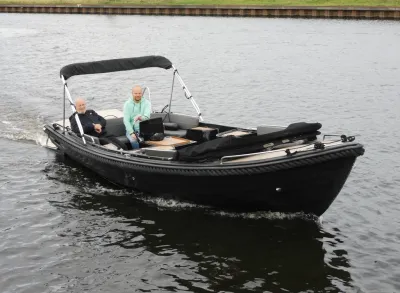 zwarte sloep met twee personen op het water