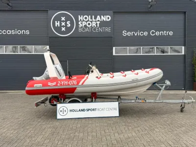 Rode en grijze RIB op trailer bij bedrijfspand