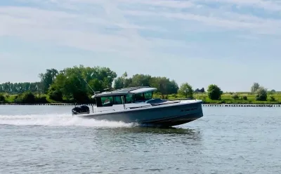 Motorboot varend op water met oever op achtergrond