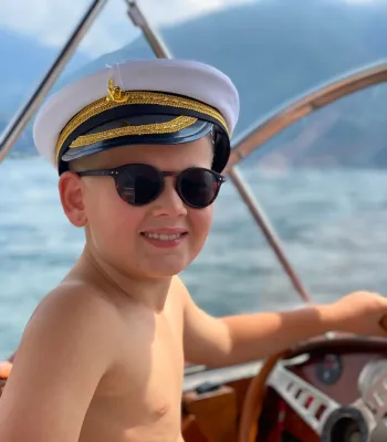 jongen met kapiteinspet op een houten boot