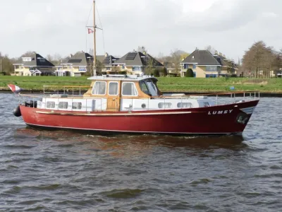 rood motorjacht op rivier met huizen op de oever