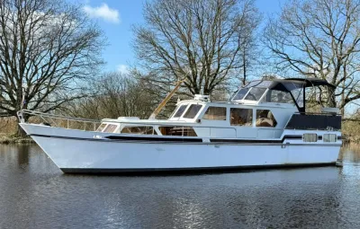 witte kruiser op rustig water bij bomen