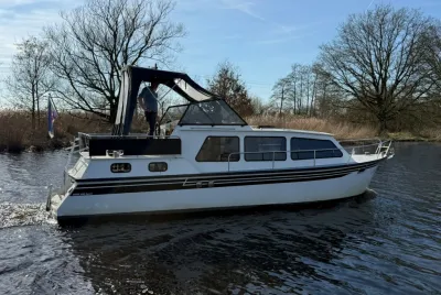 wit motorjacht op rivier met persoon aan dek