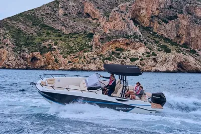 motorboot met opvarenden bij rotskust