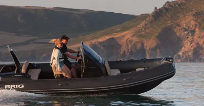 RIB met twee personen bij rotsachtige kust