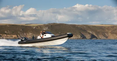 RIB-boot op zee met kust en wolken op de achtergrond