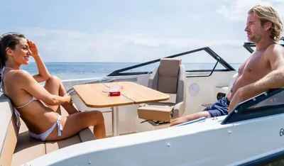 twee personen op open motorboot bij kust