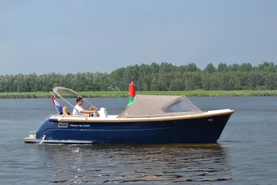 Motorboot op water bij boei en groene oever