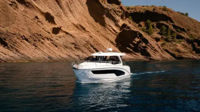 witte sportcruiser op zee bij rotsachtige kust